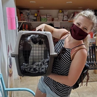 image of woman holding cat in a crate